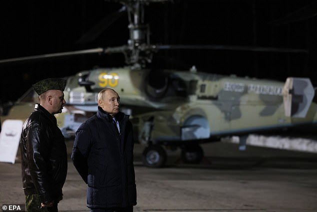 Russian President Vladimir Putin (2-L) speaks with Hero of Russia, head of the center's air weapons training and tactical training, Alexander Karamyshev (L)