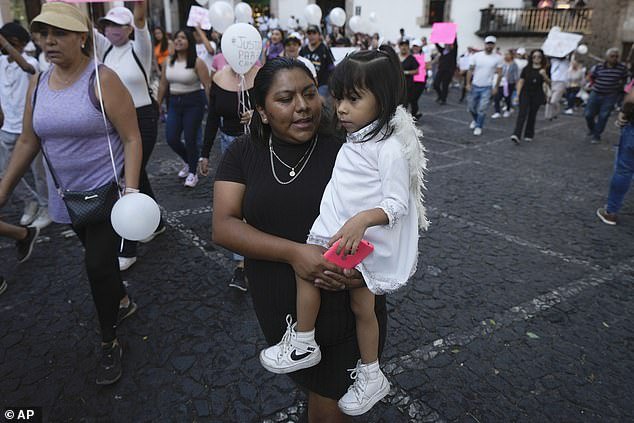 A woman carries her daughter during a demonstration against the kidnapping and murder of an 8-year-old girl, in the main square of Taxco, Mexico, Thursday