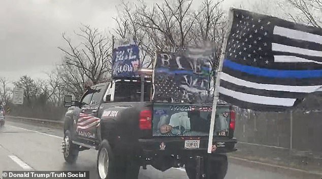 An image of the current president, tied up, was on the back of a large truck with multiple flags in support of law enforcement and a license plate with red 