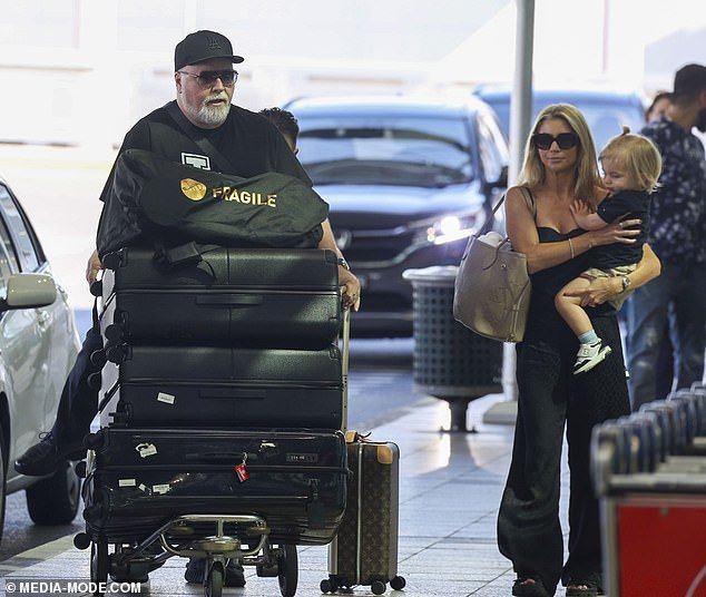 Kyle completed his look with a black baseball cap and carried his essentials in a small shoulder bag, while also carting their luggage around.