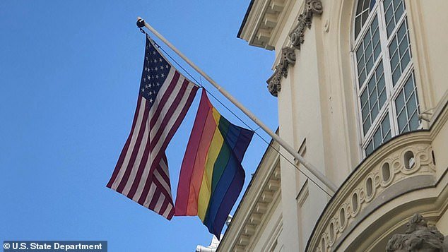 A rainbow flag is raised on a pole beneath the American flag outside the U.S. Embassy in Vienna, Austria