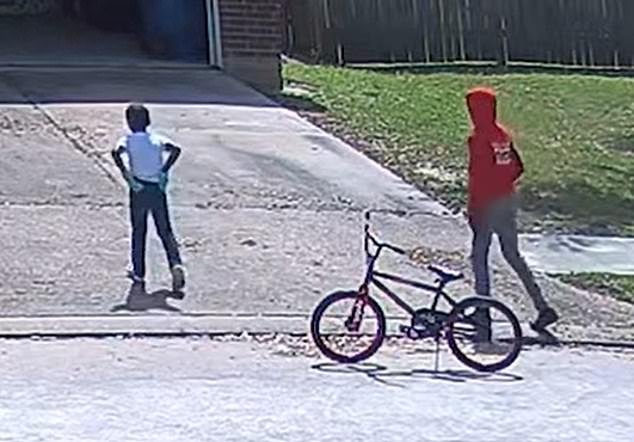 Footage from a surveillance camera at a neighbor's home shows the shorter boy wearing blue gloves and the taller boy in a red hoodie with black gloves walking into the woman's driveway.