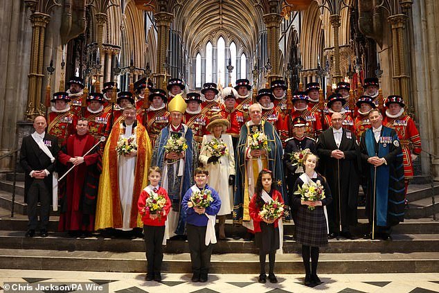 Queen Camilla holds the Nosegay's bouquet as she poses with Yeomen of the Guard and religious representatives during the Royal Maundy service at Worcester Cathedral today