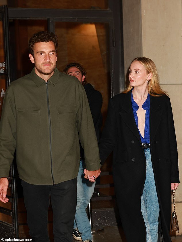 Sophie went braless under a chic blue shirt which she wore open and a long wool coat over it
