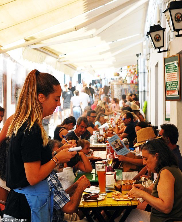 File photo shows a waitress taking an order on a terrace of a Tapas bar in Conil de la Frontera, near Cadiz, during a busy lunch time