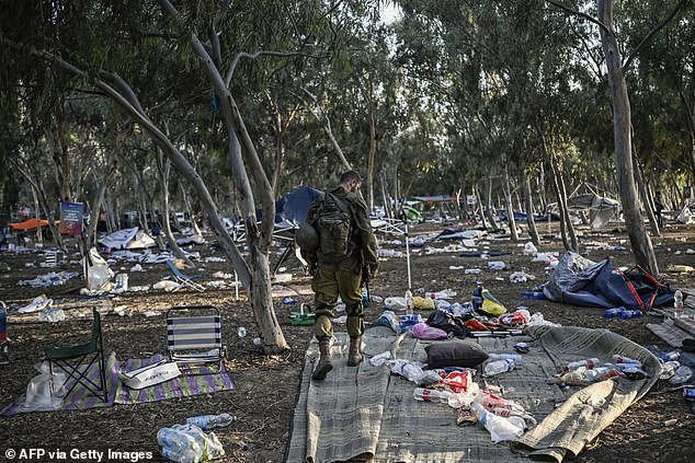 An Israeli soldier assesses the damage caused by Hamas militants' invasion of a music festival, where they killed 360 civilians