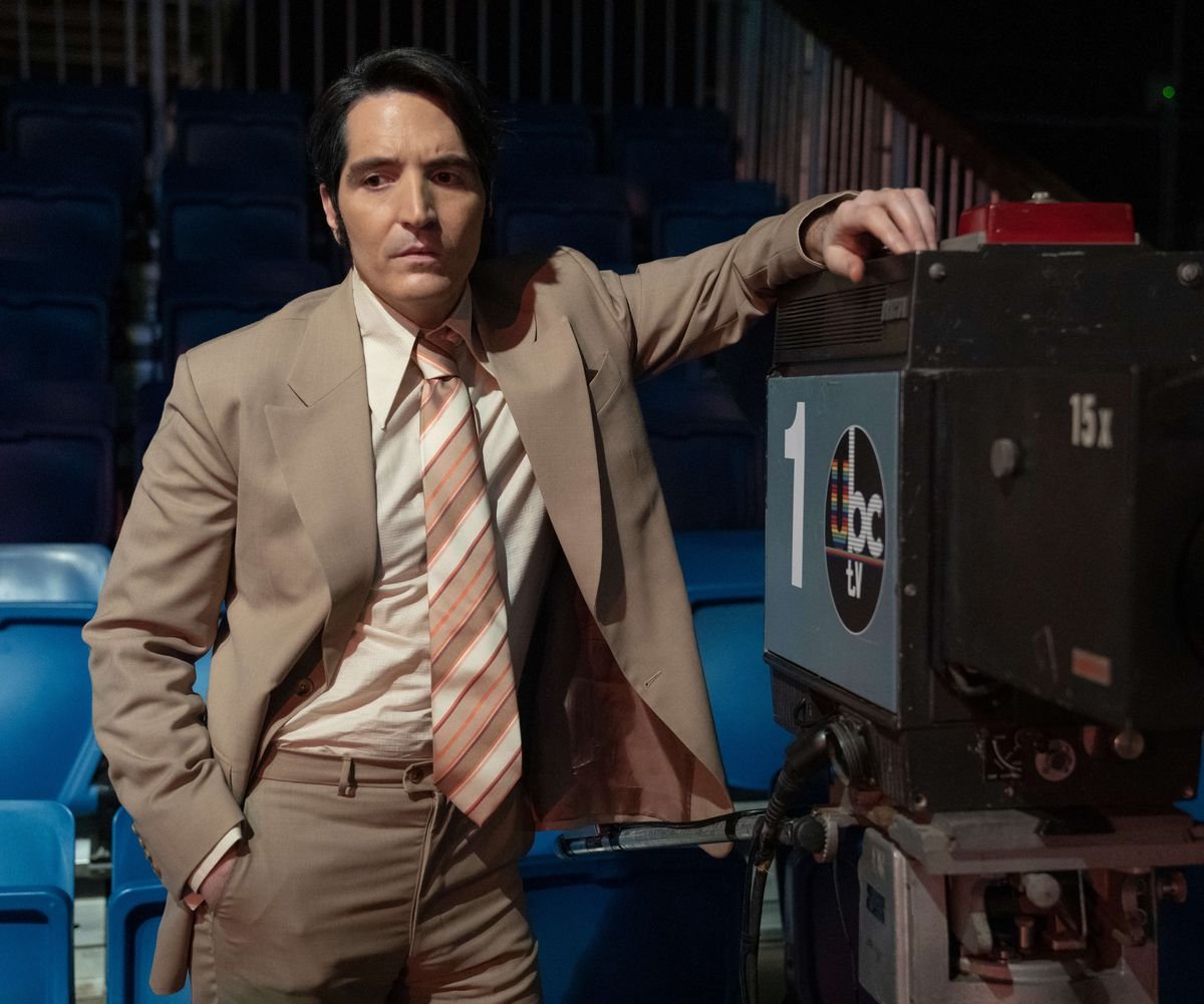 David Dastmalchian as Jack Delroy in Late Night with the Devil, wearing a suit and leaning against a camera