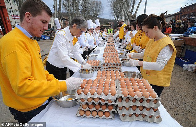 About 50 volunteers work together to make the giant omelet, breaking eggs and stirring the large pan