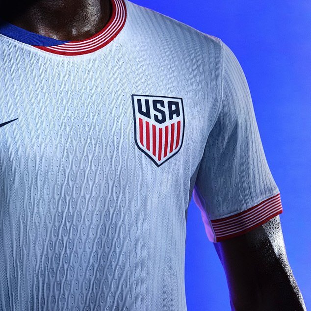 The white home shirt has red and blue details and is paired with navy blue shorts