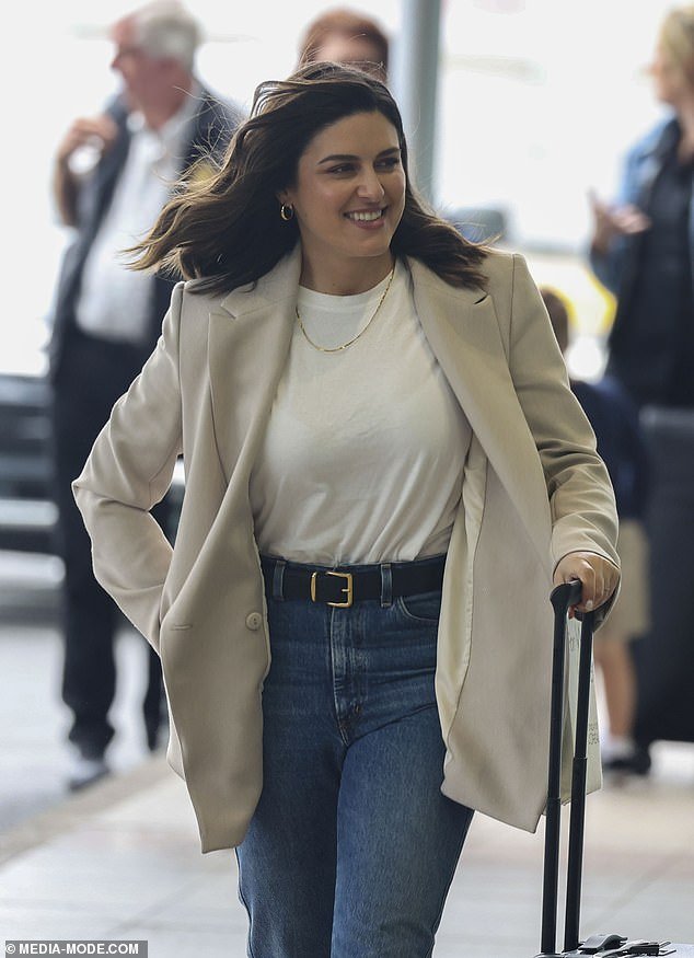 Sarah Abo was all smiles, wearing a stylish beige jacket over a white shirt and jeans