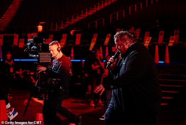Photos from Saturday's rehearsals gave an idea of ​​what Jelly Roll's performance will entail.  One shows him walking down the stairs among the crowd as red lights shine into the arena