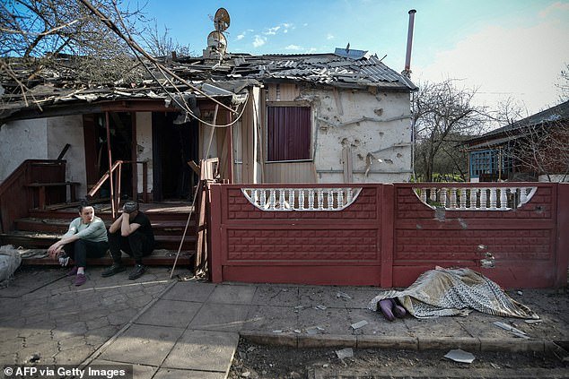 People sit in front of a house hit by recent shelling, what local officials called a Ukrainian military attack, in Donetsk, Russian-controlled Ukraine, on April 7, 2024.