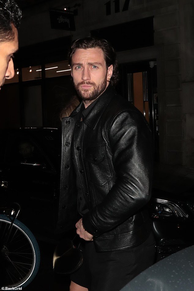 Aaron cut a smoldering figure in a black leather jacket, styled with a black shirt and jeans