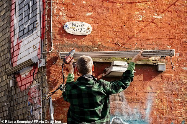 A resident of the Christiania neighborhood takes down a neon light on a building on Pusher Street