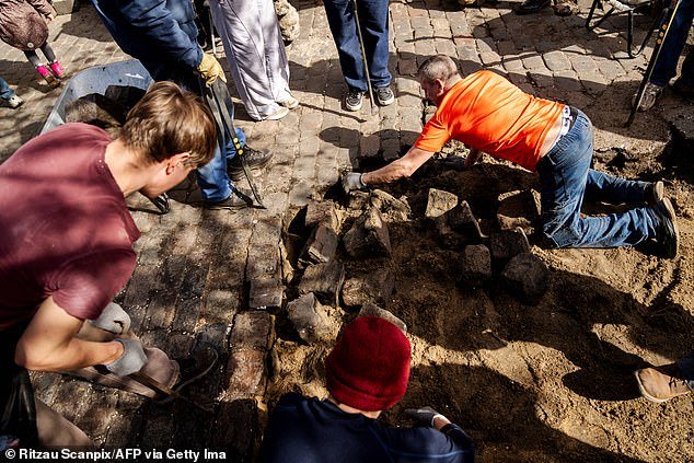 Residents of the Christiania neighborhood jointly dig out the cobblestones of Pusher Street