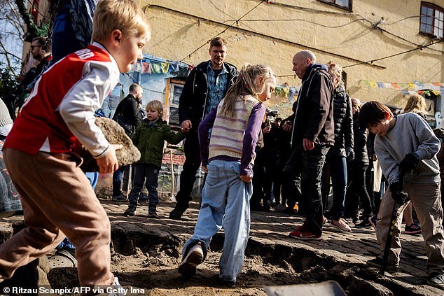 Children participate as residents of the Christiania neighborhood dig out the cobblestones on Pusher Street