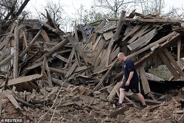A local resident walks through the ruins of a house destroyed by recent shelling, which local Russian-installed authorities called a Ukrainian military attack