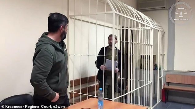 Lyutyi is seen in a cage in a courtroom during his trial