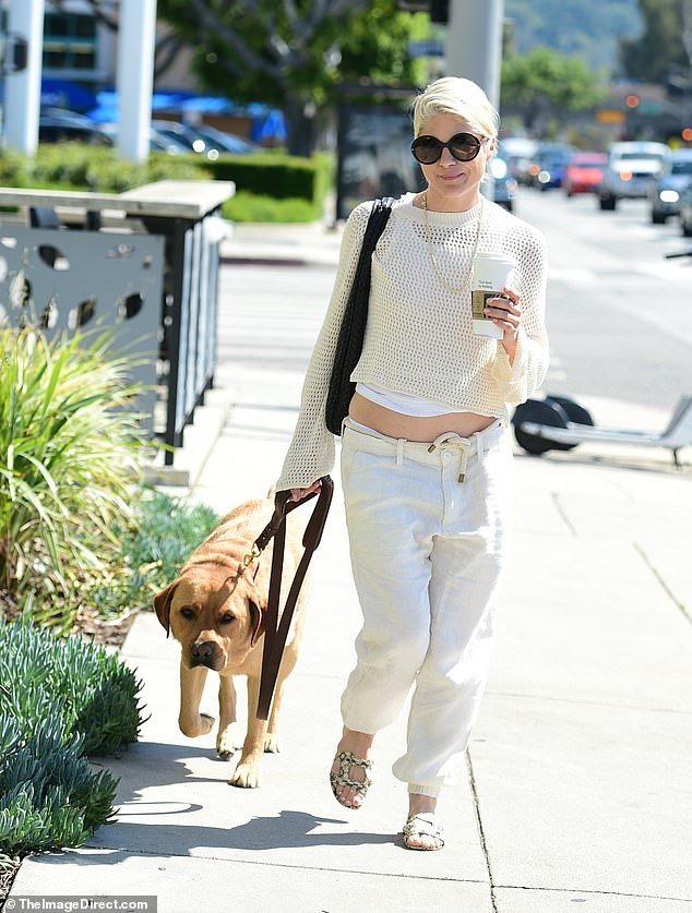 She went for a monochromatic white ensemble and wore oversized low-rise jeans with a thick cream rope as a belt.  She donned a pair of patterned strap-on sandals on her dog walk for a mid-day pickup from a coffee shop