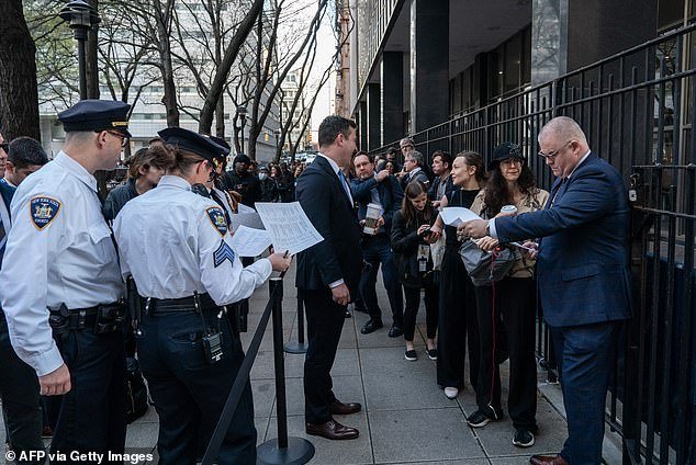 Members of the media line up and are checked off the list to enter Manhattan Criminal Court for the first day of the trial of former US President Donald Trump