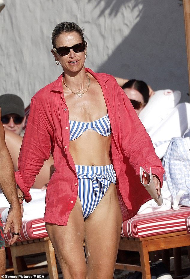 Vogue, 38, looked stunning in a blue and white striped bikini, with a pink shirt over the high-waisted two-piece