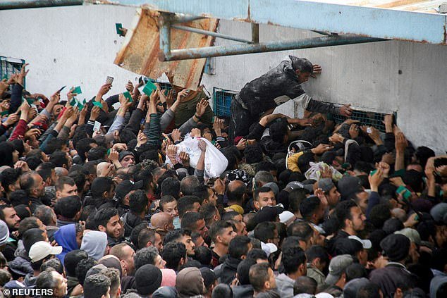 Palestinians gather to receive aid outside an UNRWA warehouse as Gaza residents face a hunger crisis, March 18, 2024