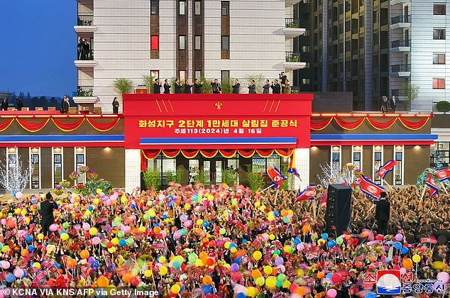 “Completion ceremony for 10,000 households second phase of Hwaseong district on April 16,” read the yellow Korean text on the stage, which rises above an adoring crowd below