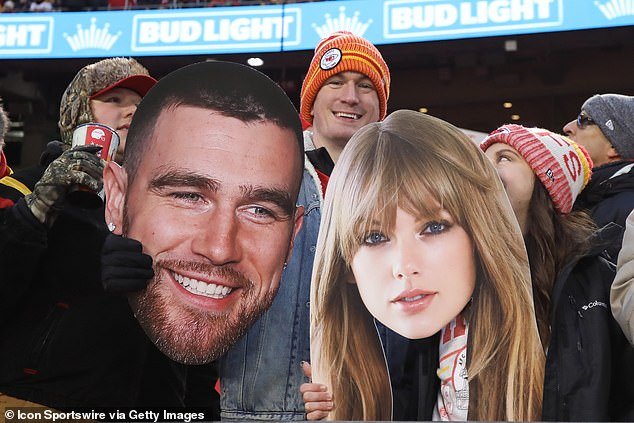 Fans hold large photos of Travis Kielce and Taylor Swift at an NFL game on December 31