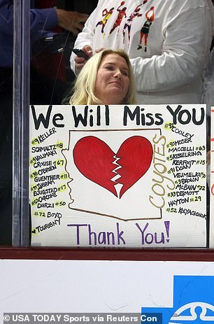 A fan holds a sign against the glass for the Coyotes in their final home game before moving