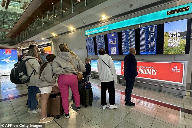 Passengers check flight information on screens at Dubai International Airport on Wednesday