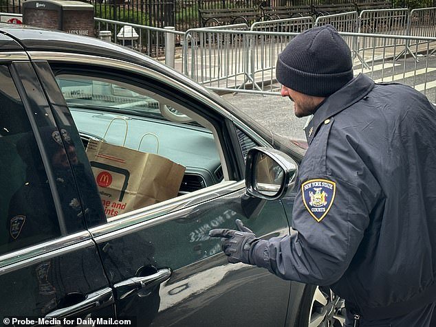 An officer greets the vehicle carrying former President Donald Trump's McDonald's run in New York on Thursday, day three of the hush money trial of Stormy Daniels