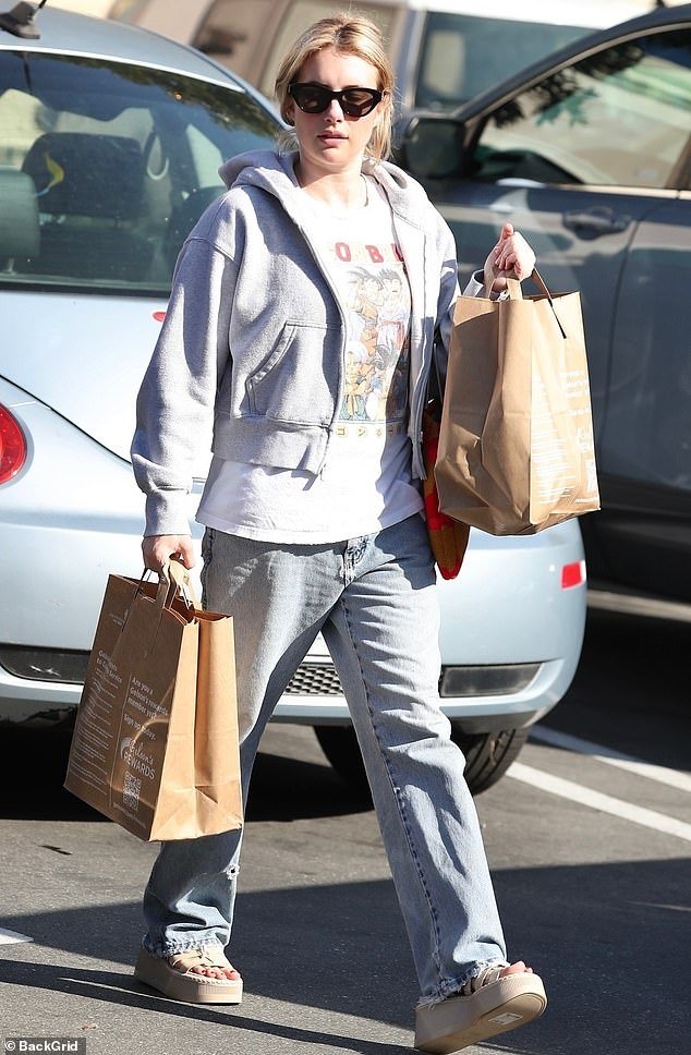She wore the top under an open gray hoodie, paired with faded jeans and chunky beige sandals