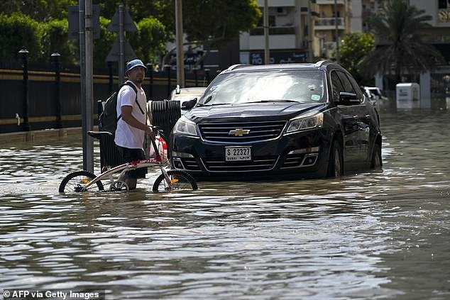 A man crosses a flooded street after heavy rain in Sharjah on April 17, 2024