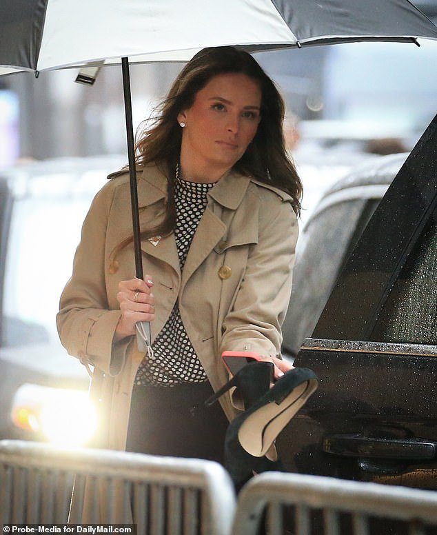 She is seen here with a pair of black suede pumps in hand on a rainy Thursday outside the court