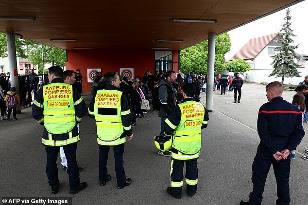 Parents pick up their children under the supervision of police and firefighters at a school in the eastern French city of Souffelweyersheim after two girls were injured in a knife attack outside the school on April 18, 2024