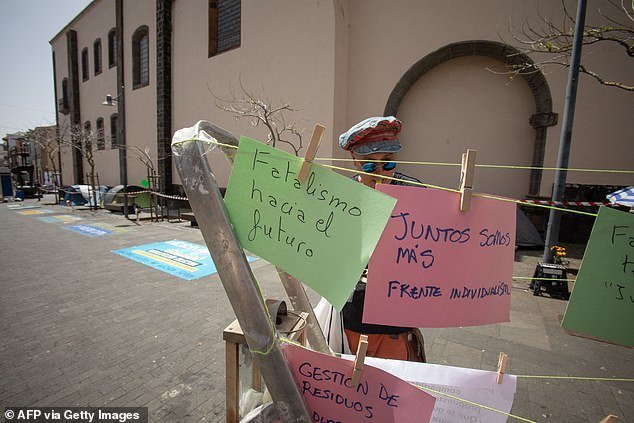 A man hangs signs written by demonstrators next to tents of activists on hunger strike to protest mass tourism infrastructure in La Laguna, on April 13, 2024