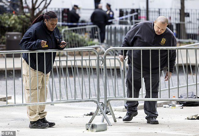 Police officers investigate a canister of flammable liquid left where a man set himself on fire in Collect Pond Park, outside Manhattan Criminal Court