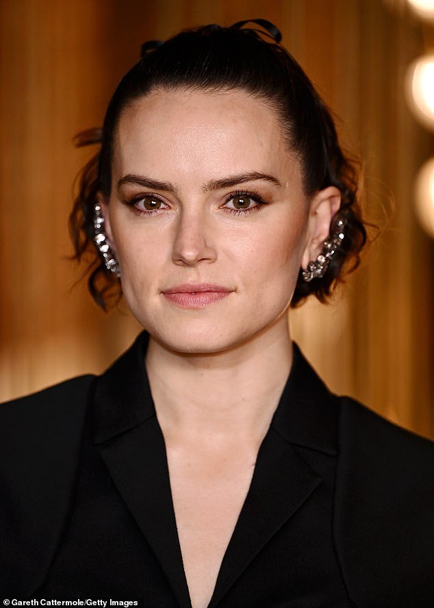 Daisy secured her brunette locks with a black ribbon and accessorized her look with some beautiful silver earrings that covered the full length of her ear.