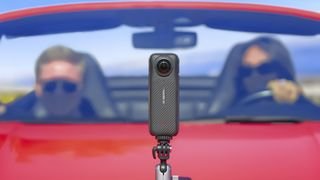 Insta360 X4 360 degree camera mounted on the hood of a red convertible