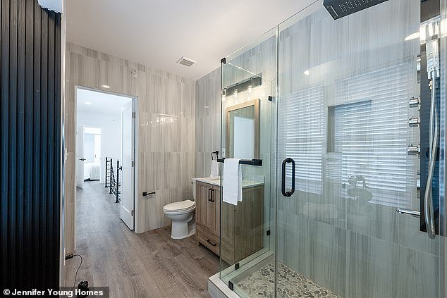 The large-looking but deceptively small bathroom has a large glass shower with a cobblestone floor and beautiful wooden finishes