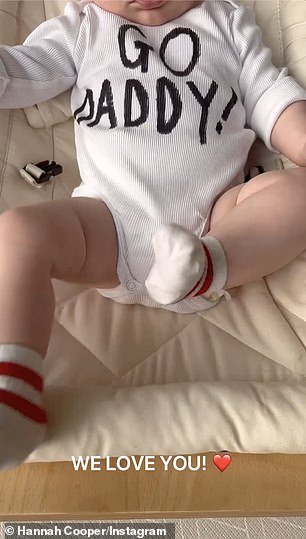 The little one was seen kicking his stocking feet while wearing a baby romper with 'GO DADDY' written on the front
