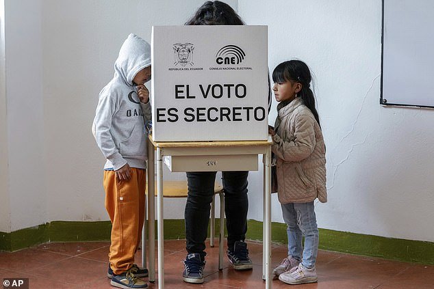 Children stand with a voter and ask questions on the ballot of a referendum proposed by President Daniel Noboa to approve new security measures aimed at cracking down on criminal gangs fueling escalating violence