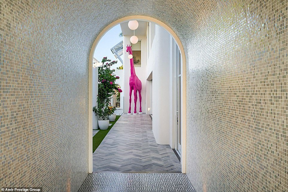 Visitors enter the unique home through a curved mosaic tunnel and are greeted by a five-meter-tall, bright pink giraffe that has been playfully crafted to look as if it has gnawed one of the pendant lights from the roof