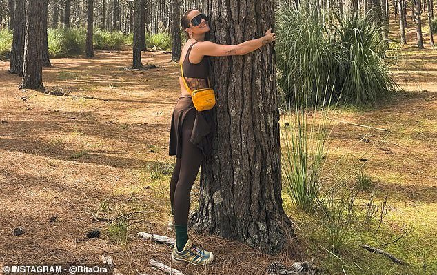 On another day in the woods, Rita wore a brown gym set with a crop top, an orange bag and hugged a tree