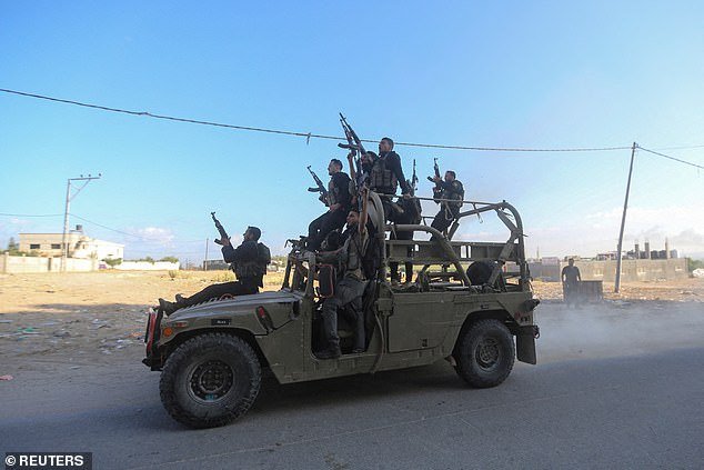 Palestinian militants ride in an Israeli military vehicle seized by armed men infiltrating areas in southern Israel, northern Gaza Strip, on October 7, 2023