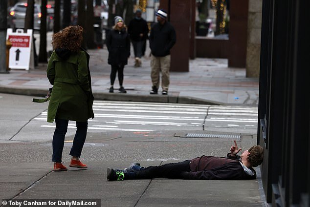 Synthetic opioid users often lie on the streets, lost in the grip of substance abuse.  Pictured: A man suspected of being under the influence of drugs in Seattle