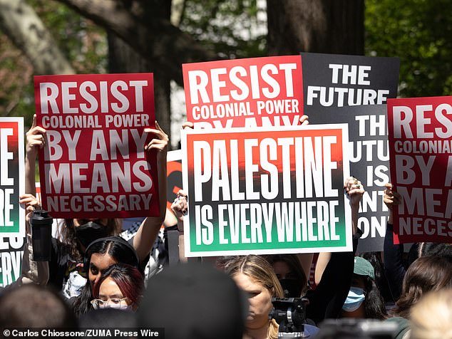 A group of NYU students, faculty and supporters hold signs to liberate Palestine during a rally in Washington Square Park