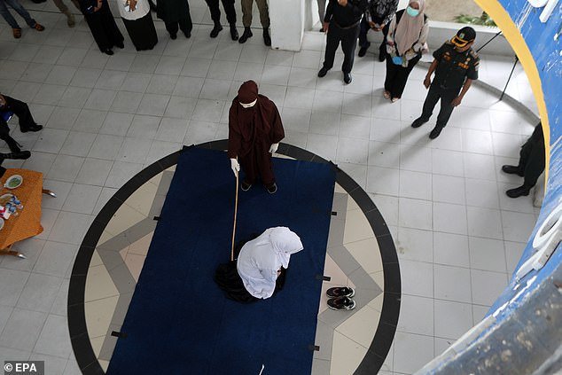 An Aceh woman is caned in front of the public for violating Sharia law