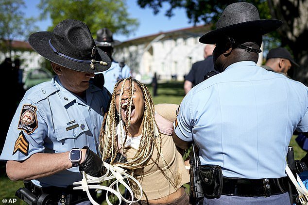 Another female protester screams as two Georgia State Patrol officers hold her arms.  One of the officers (left) is seen carrying a bundle of white zip ties