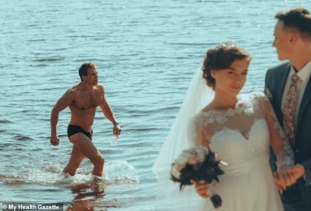 A happy couple posed for photos on the beach before a swimmer captured the special moment